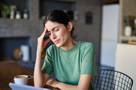 Portrait of a young woman with laptop or tablet with a headache  frustrated, stress anxiety problem concepts at home