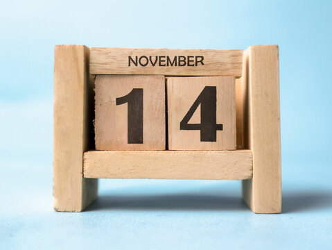 A wooden block calendar for November 14th on a light blue background.
