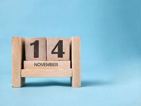 A wooden block calendar for November 14th on a light blue background.