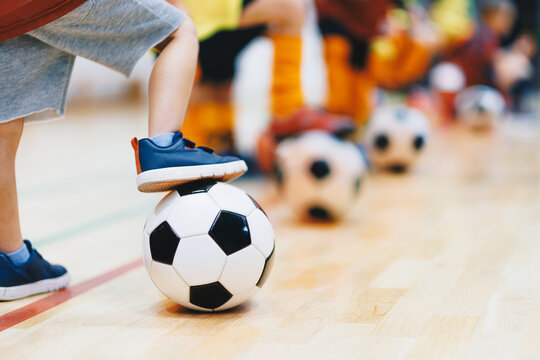 Close-Up View of Junior Player Foot Resting on Soccer Ball During Indoor Futsal Training - Gymnasium Floor Action