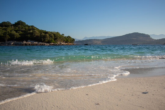 Low-Angle View of Turquoise Waves Washing onto the Sandy Beach in Ksamil during a Sunny Morning in Albanian Riviera.