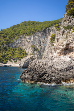 Vertical Coastal Landscape from Keri Area in Zakynthos, Greece. Crystal-Clear Turquoise Ionian Sea alongside Rugged Rocky Cliffs with Lush Green Trees. 