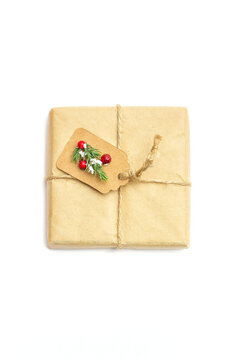 View of a Christmas present in homemade craft paper packaging with red berries on white isolated background, top view, flat lay