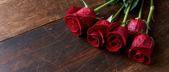 Fototapeta premium Five red roses with water droplets arranged on a dark wooden surface
