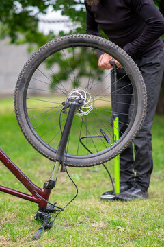 Man Pumping Bicycle Tire with Portable Pump in Park