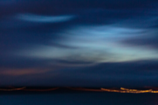 Puget Sound, view to the lights of the city on the coastline at night, the ocean surface at night, motion blur.