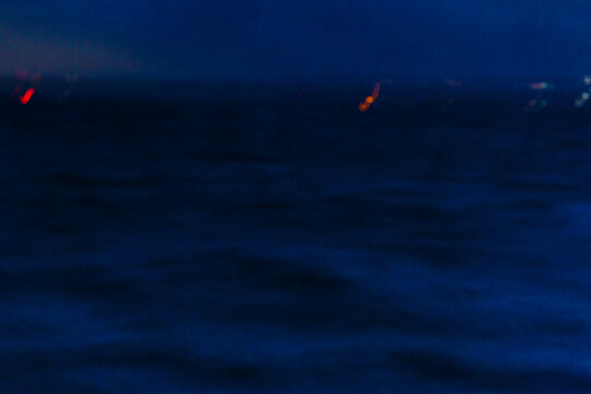 Puget Sound, at night, two red pinpoints of light, reflections on the water surface. 