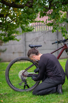 Bearded man repairing bicycle on grassy lawn