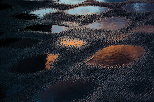 Puddles of water on the top deck of a boat on Puget sound, reflections of light from the water.