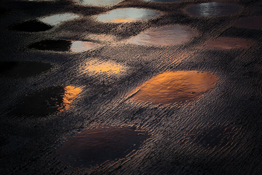 Puddles of water on the top deck of a boat on Puget sound, reflections of light from the water.