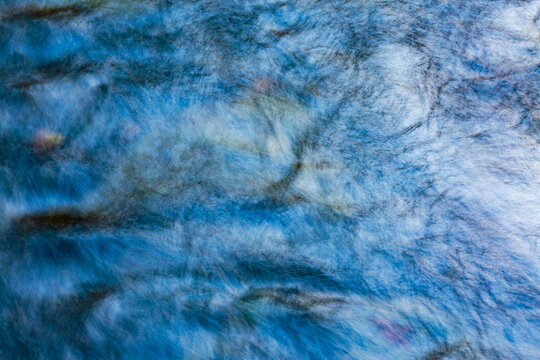 Flowing water, motion blur, long exposure of the surface of moving water in a river.