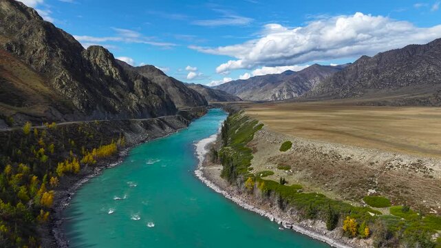 Aerial tracking shot of winding mountain turquoise river canyon in autumn.