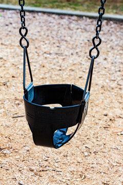 Children's bucket seat swing in play area.
