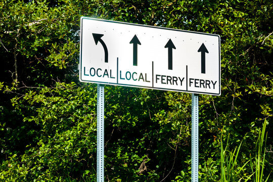 A roadsign with arrow direction information for local traffic and ferry traffic.