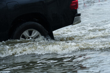 Fototapeta premium A vehicle is driving through deep floodwaters on the road. 