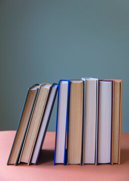 Row old hardcover books, balancing upright on shelf