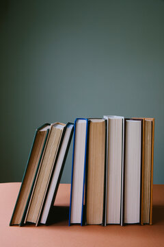 Row old hardcover books, balancing upright on shelf