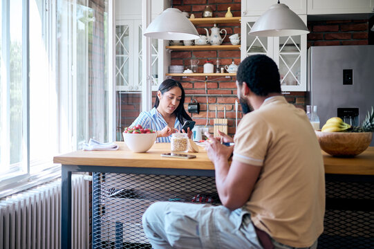 Couple ignoring each other while using smartphones during breakfast