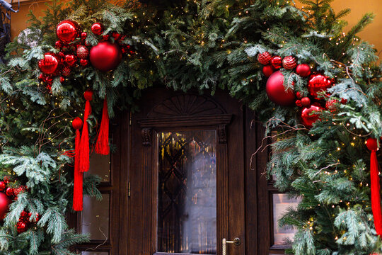 Christmas archway entrance decorated with evergreen pine branches, red baubles, tassels and fairy lights. Christmas street decor