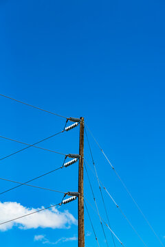 Telephone pole and wires, communication lines against a blue sky.