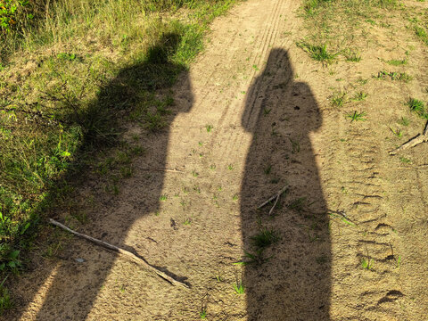 Long Human Shadows on Sandy Forest Path at Sunset