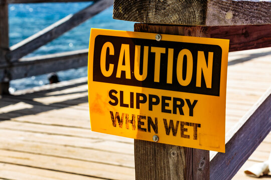 Caution, Slippery When Wet sign on old wooden dock on lake, Port Angeles