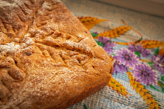 Homemade rye bread with cranberries, a richly browned crust, flour-dusted surface, and decorative scoring forming a distinctive branching pattern
