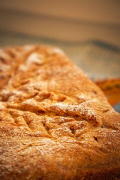 Rustic homemade loaf with a crisp golden-brown crust, fine flour dusting, and distinctive decorative cuts radiating across the baked surface