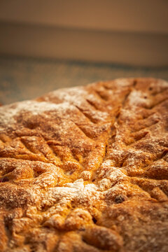 Rustic homemade bread with a deeply browned crust, flour-dusted surface, and decorative cuts forming a bold symmetrical pattern across the loaf