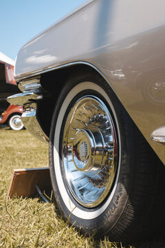 Close-up of a vintage Cadillac classic car wheel featuring a shiny chrome hubcap and clean whitewall tire.
