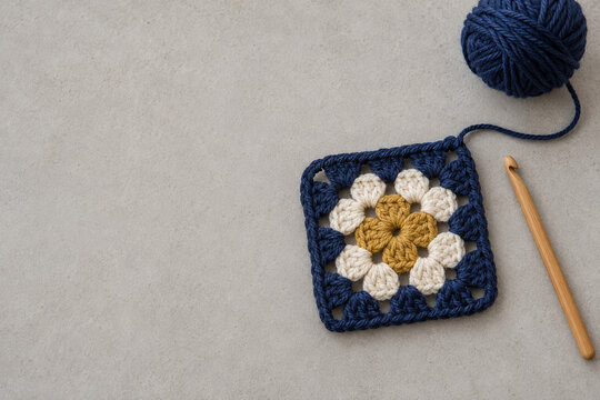 Crochet granny square with yarn and a wooden hook