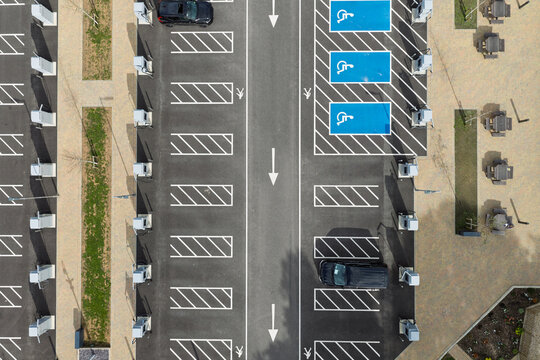 Aerial view of an electric vehicle charging station with multiple charging points, marked parking bays, and blue accessible parking spaces in the United Kingdom.
