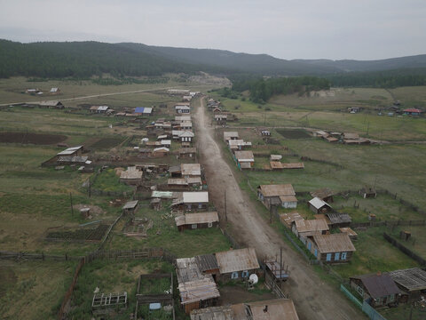 Aerial view of wooden Siberian village with unpaved road and farmland near Yelantsy, Irkutsk Oblast, Russia