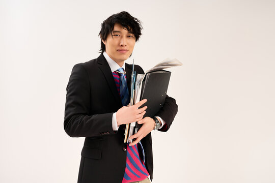 Young Asian man expressions in stylish outfit with files in hands