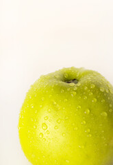 Close-up view of a green apple covered with water droplets on a light background. Fresh fruit and natural hydration concept. © Ekaterina Uteva