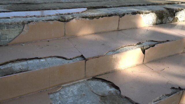 Cracked tiles expose worn concrete on outdoor steps