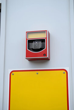 Fire safety and emergency alarm system, red wall mounted siren and strobe light with blank yellow sign for building evacuation and hazard warning