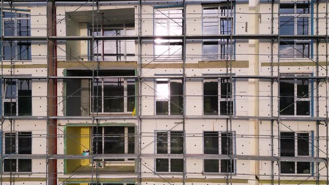 Building facade thermal insulation work with scaffolding on apartment house