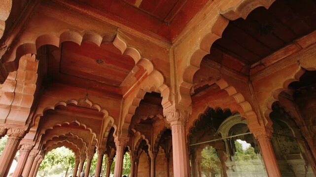 Ornate architecture of the red fort in delhi, with arches and columns leading to lush green gardens