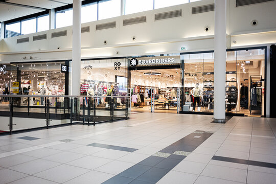 Empty modern shopping mall corridor with Boardriders store, clothing displays and bright tiled interior in Radom, Poland