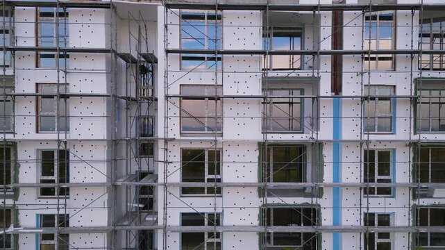Building facade thermal insulation work with scaffolding on apartment house