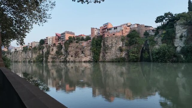 Tbilisi Cliffside Houses Above Mtkvari River
Video panorama of traditional cliffside houses and historic architecture above the Mtkvari River in Tbilisi, Georgia, with reflections on calm water at dus