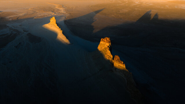 Aerial view of Bozjyra rock formations in the desert landscape with dramatic shadows cast during golden hour in Aktau, Mangystau Region, Kazakhstan.