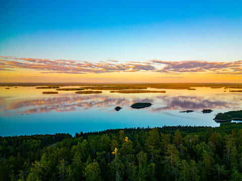 Aerial view of Koli national park featuring islands scattered across the calm lake surface during a vibrant sunset with reflections in the water in Lieksa, North Karelia, Finland.
