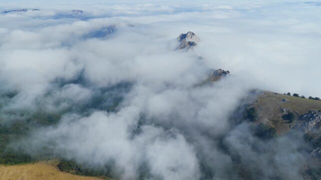 Aerial view of thick clouds rolling over limestone peaks and green valleys in Urkiola Natural Park, Basque Country, Spain
