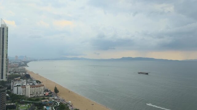 Aerial view of Pattaya beach and sea during cloudy weather before tropical storm, Thailand. Drone shot of coastal cityscape, sandy shoreline and dramatic storm clouds over the ocean, seascape concept.