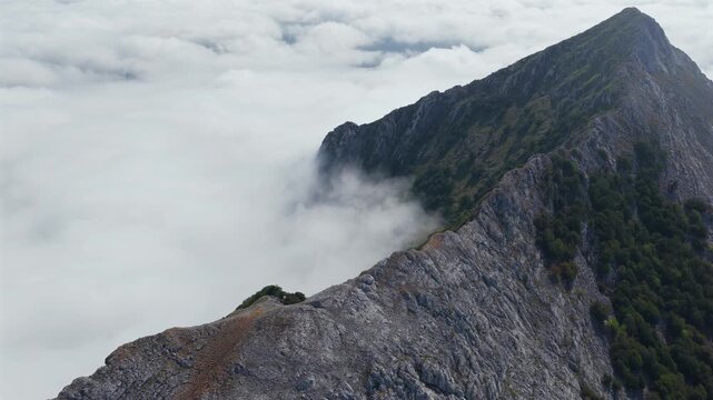 Aerial view of thick clouds rolling over limestone peaks and green valleys in Urkiola Natural Park, Basque Country, Spain