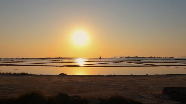 Golden sunset over tranquil salt pans near Trapani, Italy