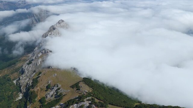Aerial view of thick clouds rolling over limestone peaks and green valleys in Urkiola Natural Park, Basque Country, Spain