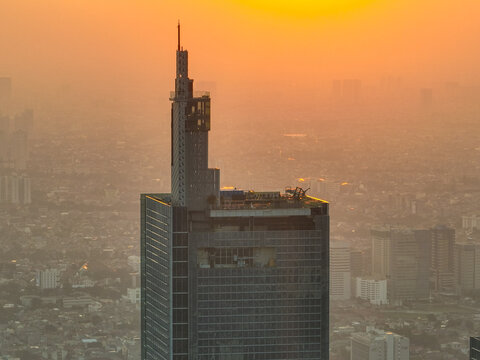 Aerial view of Autograph Tower Thamrin Nine at sunset with the surrounding urban skyline of Jakarta visible in the warm golden light, Kecamatan Tanah Abang, Daerah Khusus Ibukota, Indonesia.